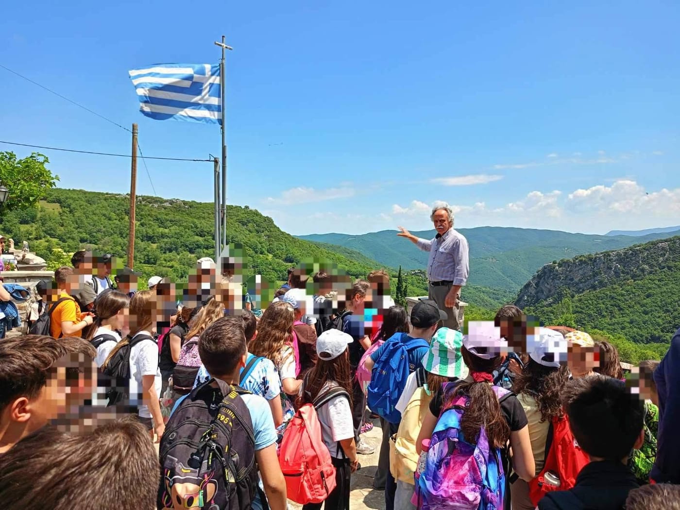 μαθητές ακούν ξεναγό με ελληνική σημαία