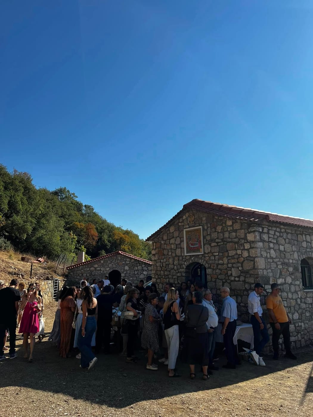πλήθος πιστών έξω από πέτρινο εκκλησάκι