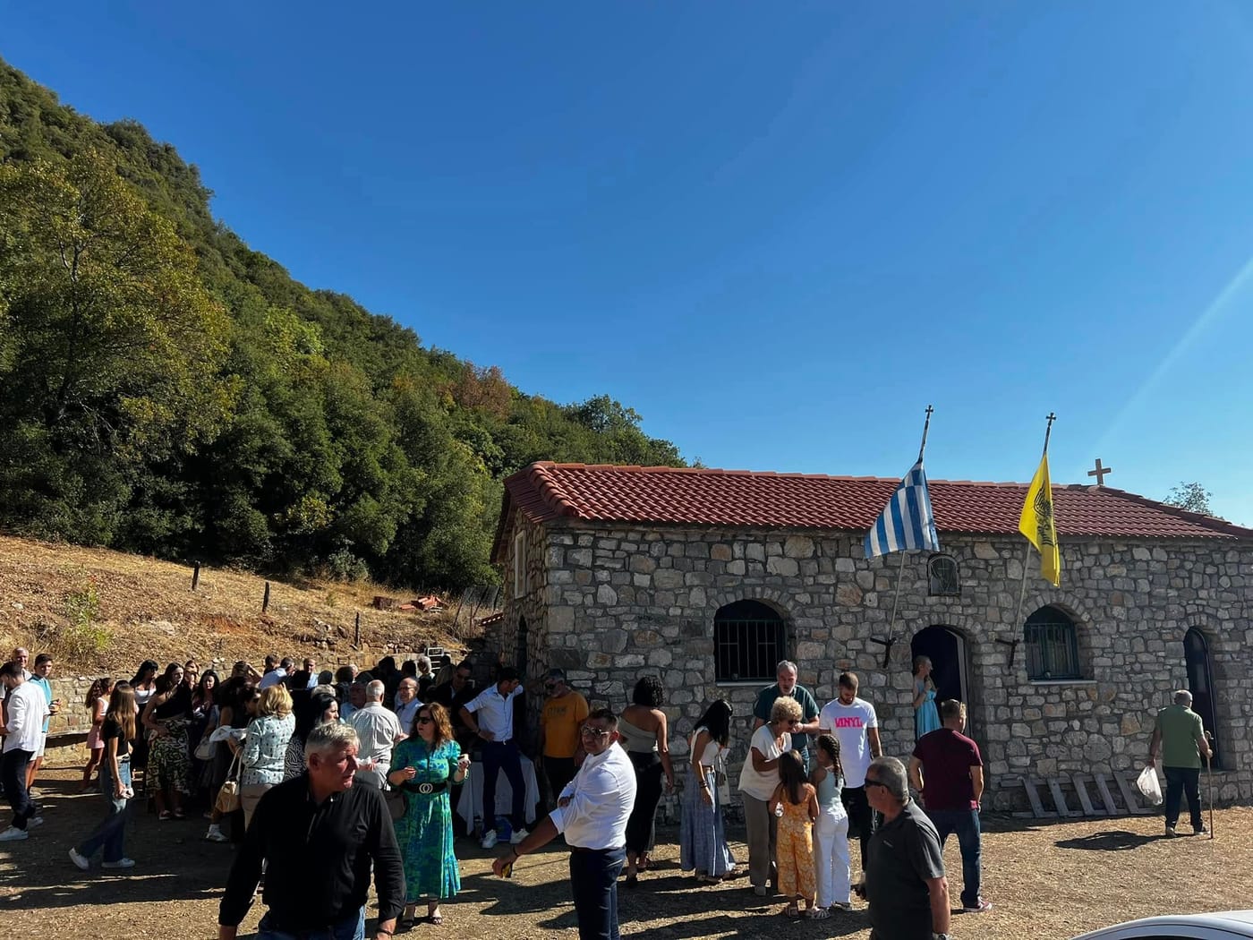 πανηγύρι με κόσμο έξω από πέτρινο εκκλησάκι